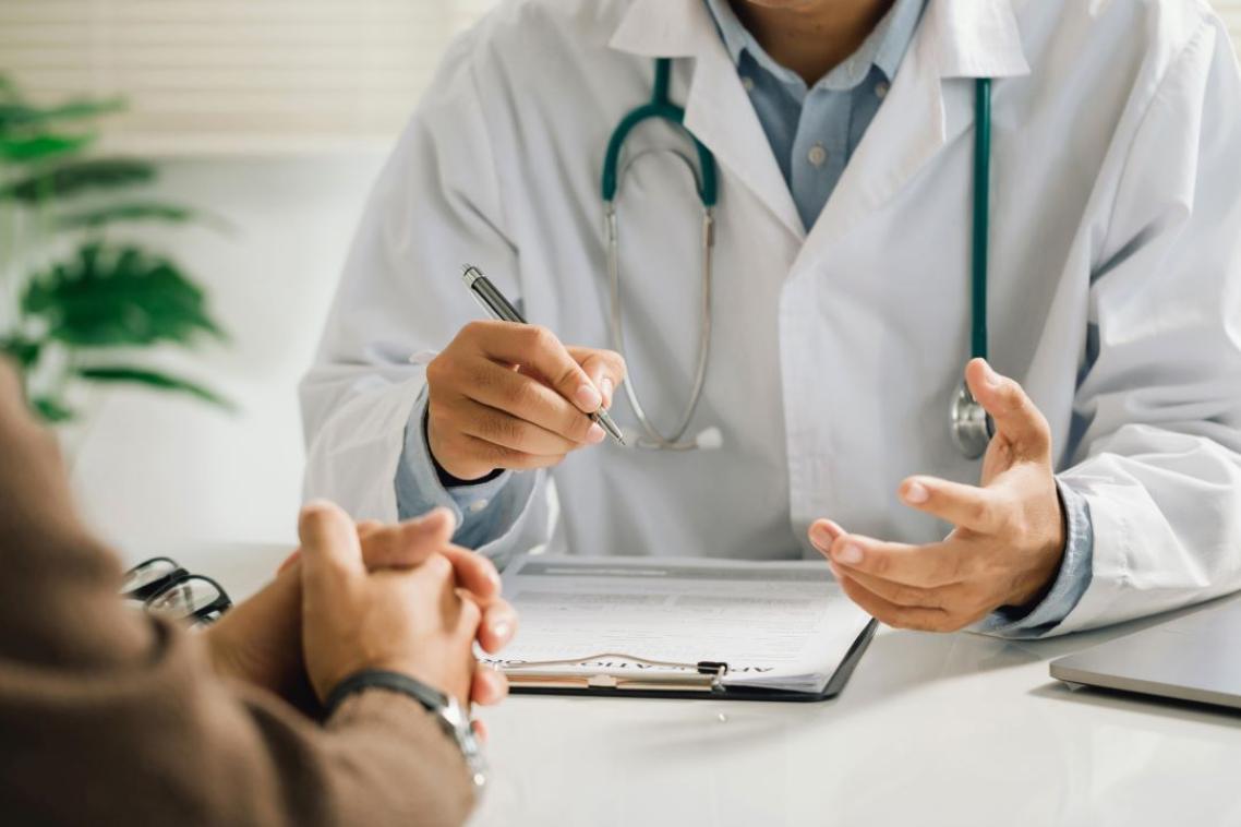 A doctor with a stethoscope talking to a patient 